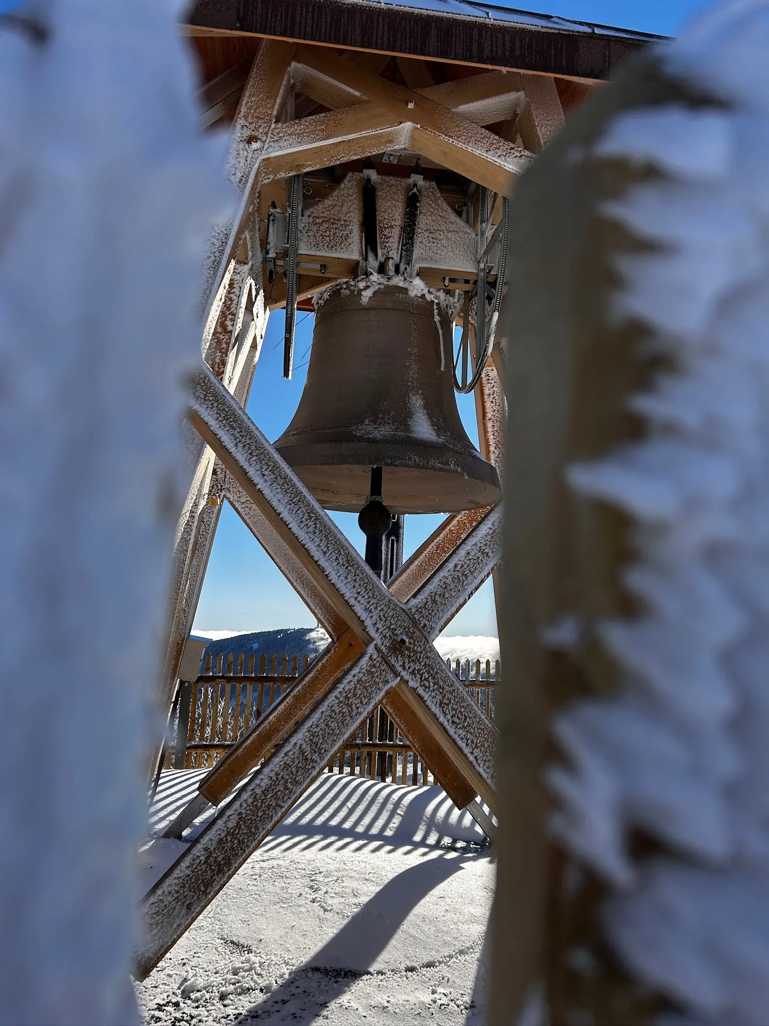 The Peace Bell Agnes framed between ice-covered fence posts