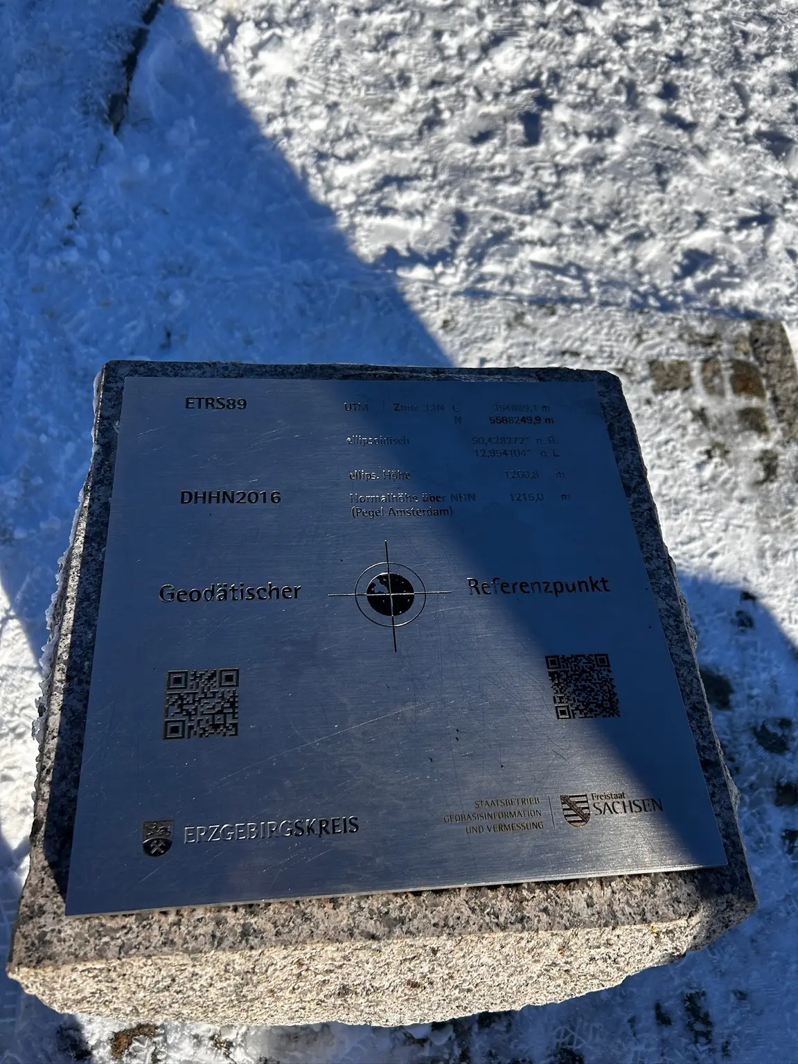 Metal geodetic reference plate showing coordinates and two different height measurements