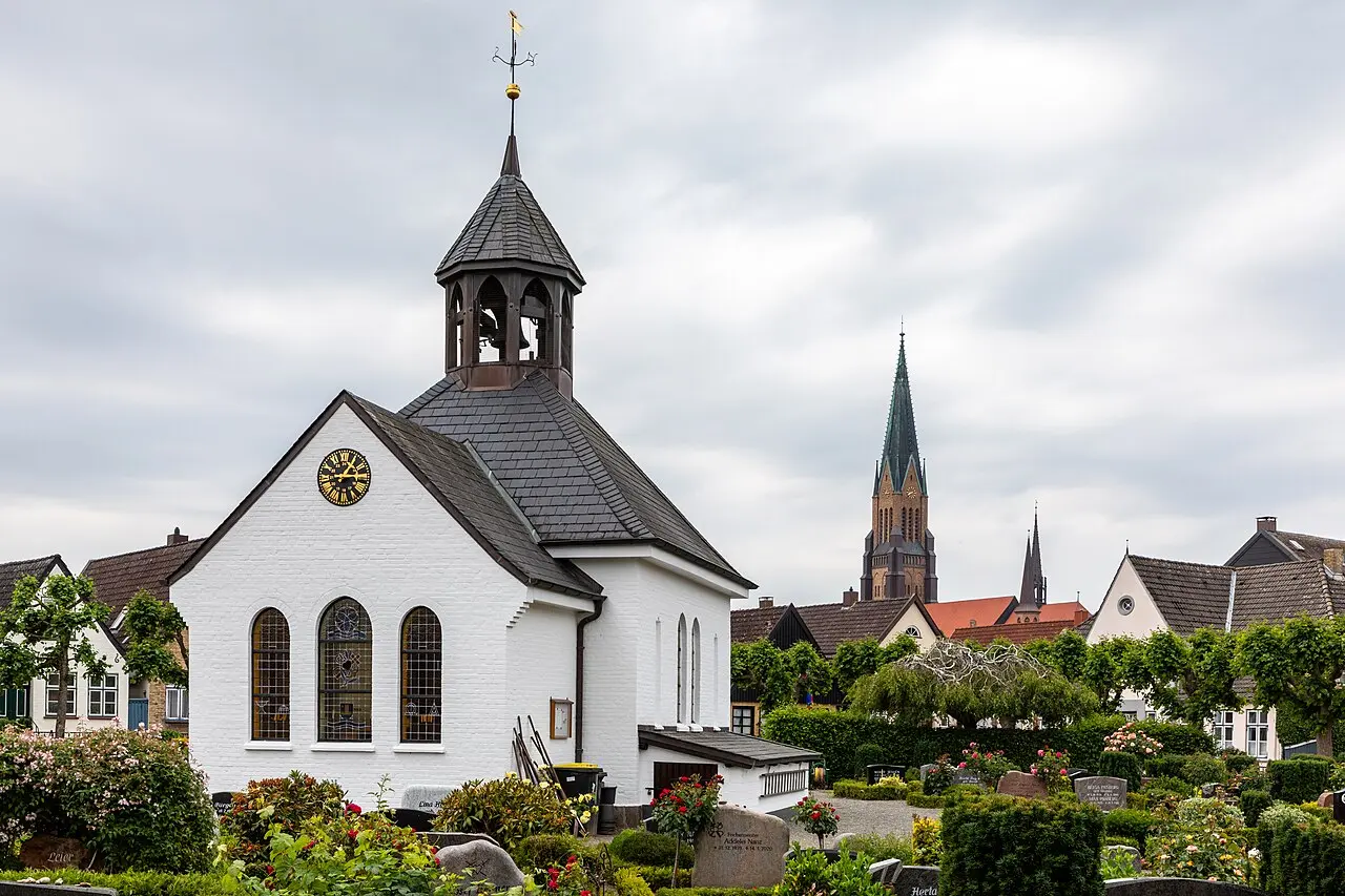 Die kleine weiße Holmer Kapelle zwischen Gräbern und alten Bäumen