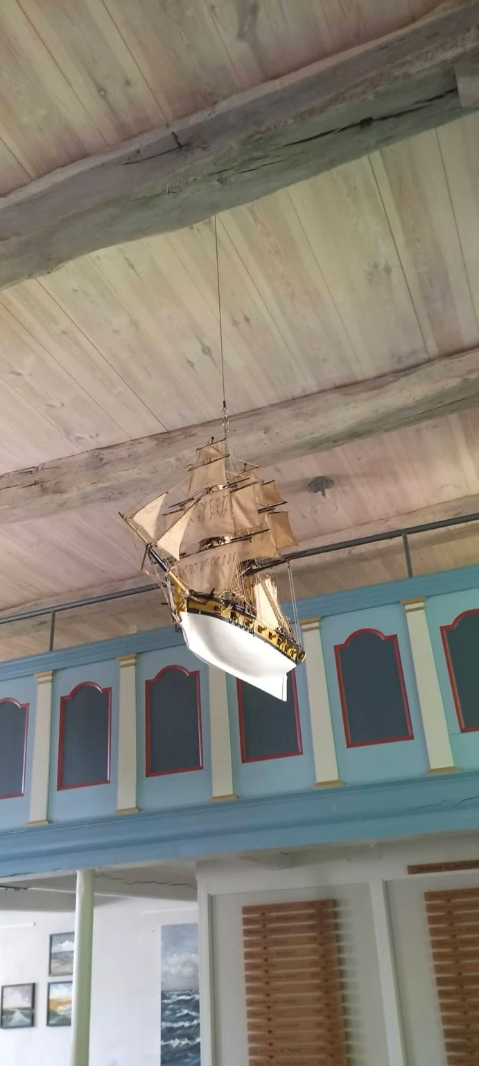 Schiffsmodell mit hellen Segeln unter den Holzbalken der Kapelle